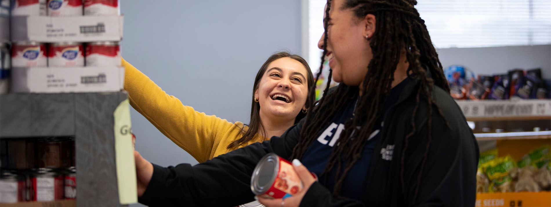 two female students restocking food pantry